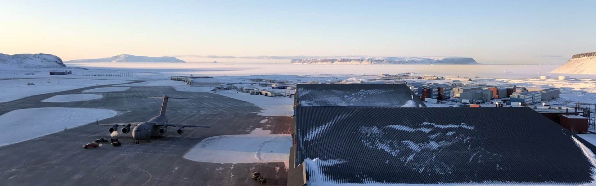 Pituffik Space Base tarmac, hangars, base facilities, and a US C-17 cargo aircraft, set amidst the frozen winter wilderness of Northern Greenland. Photo: David Palmer