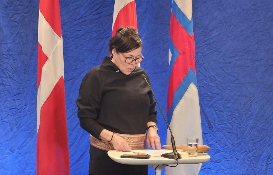 Denmark's work in the Arctic Council will be led from Greenland. Here, Greenland's Foreign Minister, Vivian Motzfeldt, is in front of the Danish, Greenlandic, and Faroese flags. (Photo: Arne O. Holm)