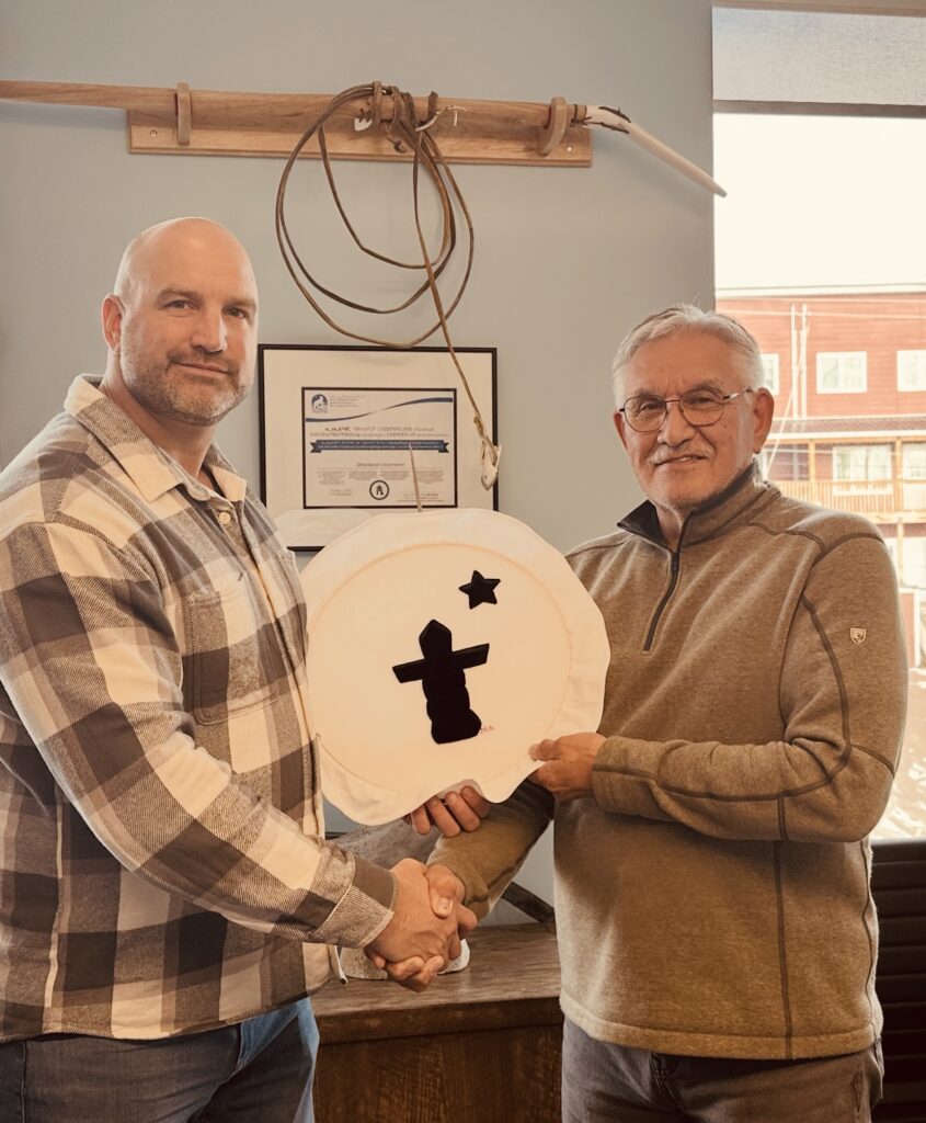 Harry Flaherty, right, CEO of Qikiqtaaluk Corporation, gives Glen Cowan, founder of ONE9, an Inuit drum Oct. 17 as a symbol of their partnership. The pair have joined together to create Sapujjijiit Inc., what they say is the first Inuit-owned defence company. (Photo courtesy of ONE9)