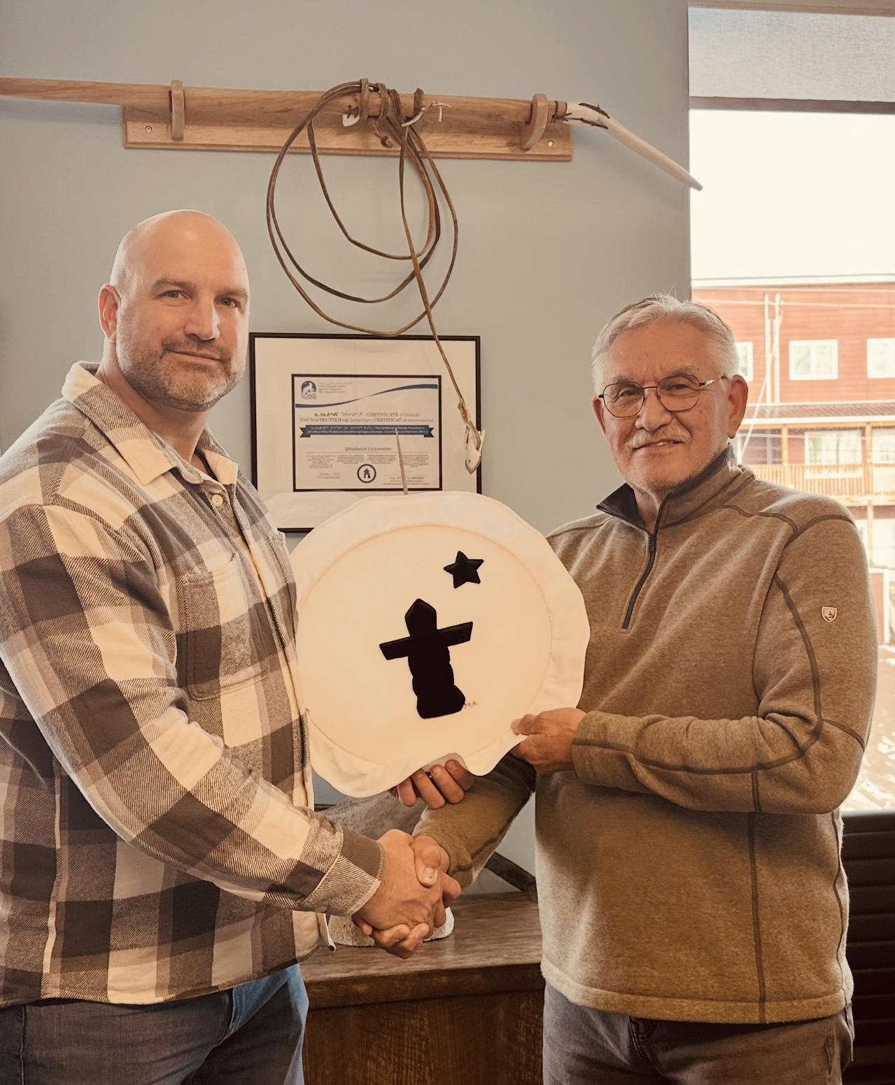Harry Flaherty, right, CEO of Qikiqtaaluk Corporation, gives Glen Cowan, founder of ONE9, an Inuit drum Oct. 17 as a symbol of their partnership. The pair have joined together to create Sapujjijiit Inc., what they say is the first Inuit-owned defence company. (Photo courtesy of ONE9)