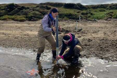Micaela Pedrazas (left) and Cansu Demir (right) install a piezometer along the beach of Kaktovik Lagoon. Photo: Bayani Cardenas.