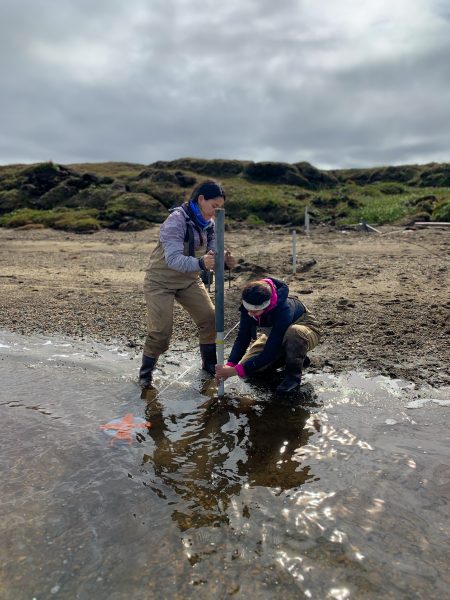 Micaela Pedrazas (left) and Cansu Demir (right) install a piezometer along the beach of Kaktovik Lagoon. Photo: Bayani Cardenas.